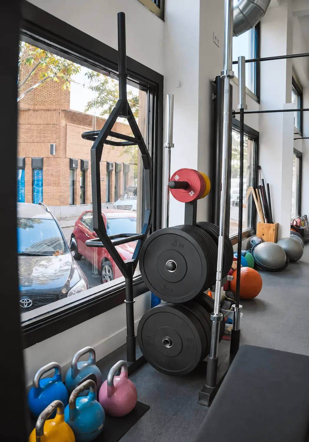 Barras, discos y kettlebells junto a los ventanales de la sala de Windfit Salud